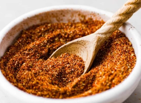 A white bowl of taco seasoning with a wooden spoon.
